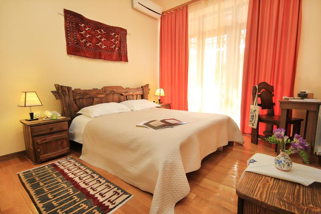 a bedroom with a bed and a window with red curtains at Silk Road Hotel in Yerevan