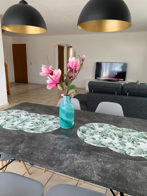 einen Tisch mit einer Vase mit rosa Blumen drauf in der Unterkunft Casa Blanca 3 in Ottenheim