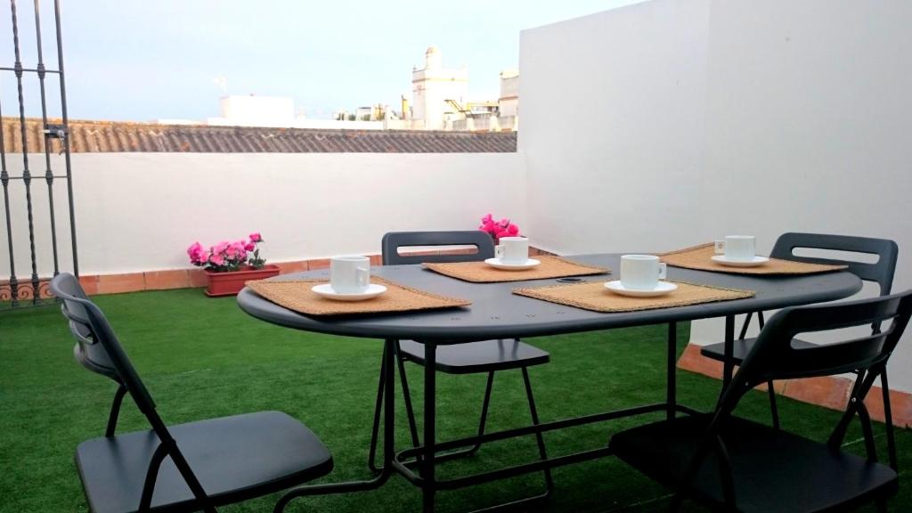 una mesa con sillas y tazas de café en un patio en One bedroom apartement with sea view furnished terrace and wifi at El Puerto de Santa Maria 2 km away from the beach, en El Puerto de Santa María