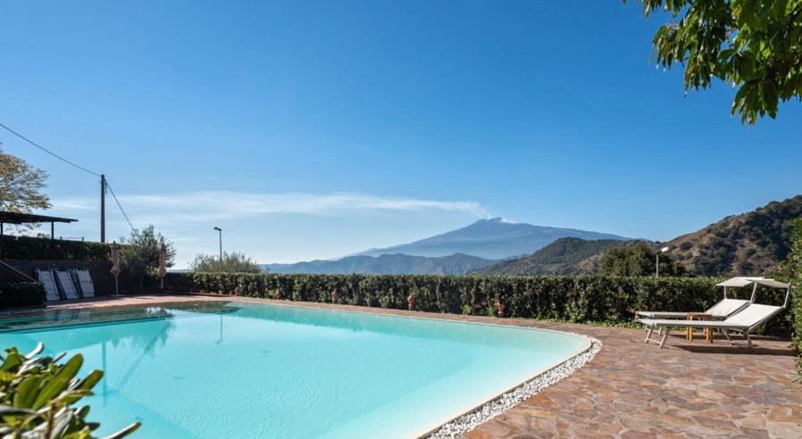 a large swimming pool with a view of mountains at Agriturismo San Cataldo in Motta Camastra