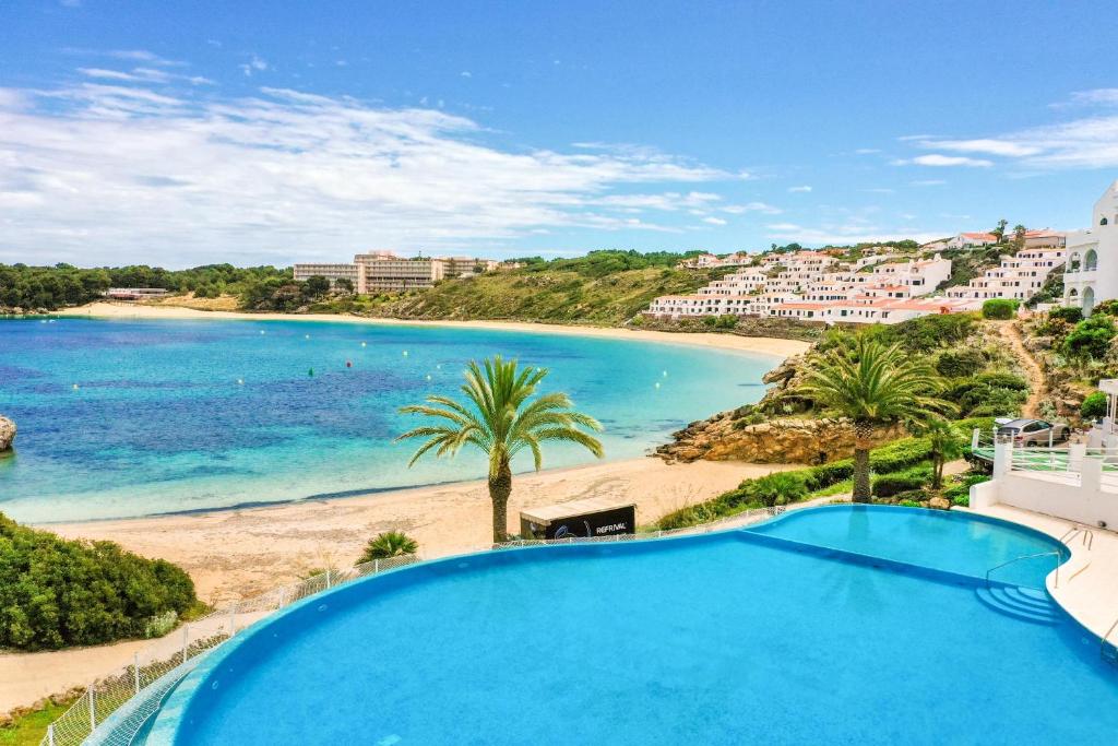 widok na plażę z basenem w obiekcie White Sands 306 w mieście Arenal d'en Castell