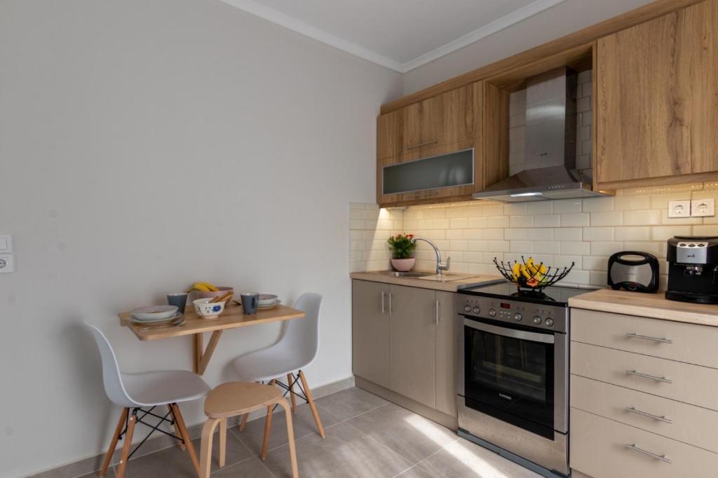 a kitchen with wooden cabinets and a small table with chairs at Elite City Apartments & Maisonettes in Lefkada Town