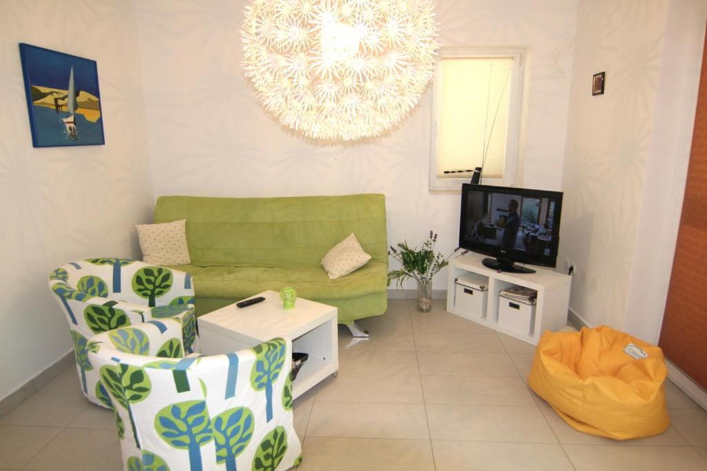a living room with a green couch and a tv at Apartment Doder in Pag