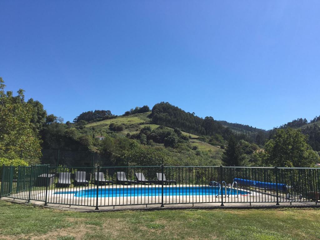 a swimming pool with chairs and a hill at Arroes Village And Pool - Villa con piscina privada in Villaviciosa