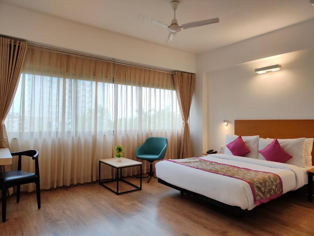 ein Hotelzimmer mit einem Bett und einem Fenster in der Unterkunft Kanak Beacon Hotel - Ashram Road Ahmedabad in Ahmedabad