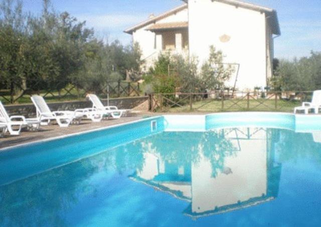 a large swimming pool with chairs and a house at Agriturismo Il Cerreto in Bettona