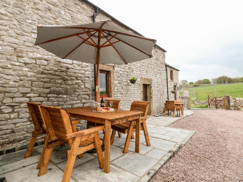 a wooden table and chairs with an umbrella at Owls Barn in Ashbourne