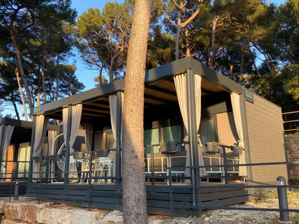 budynek z werandą z zasłonami i stołami w obiekcie Mobile Home DIVINA Camp Porton Nature Hideouts w Rovinj