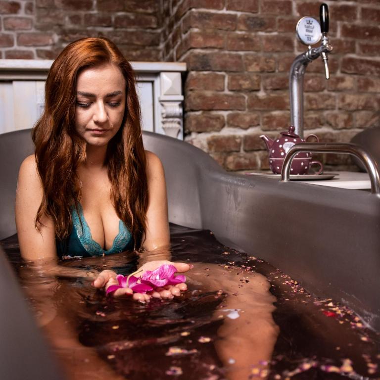 a woman in a bath tub with flowers in it at Hotel U Kata in Kutná Hora