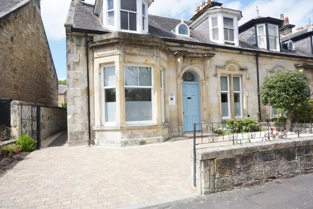 an old stone house with a blue door at Barns Serviced Accommodation in Ayr