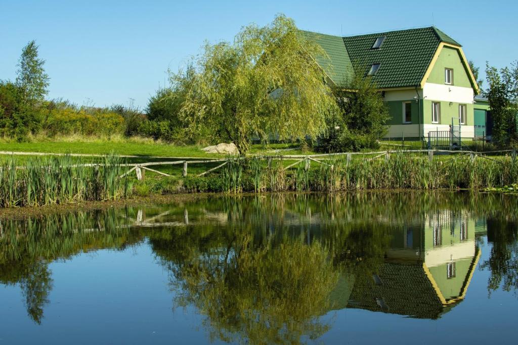 una casa reflejada en el agua de un lago en Pokoje Gościnne Butryny, en Butryny