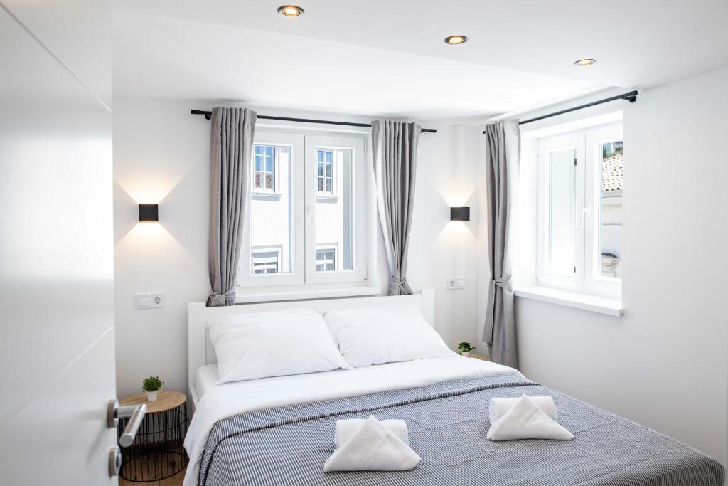 1 dormitorio blanco con 1 cama y 2 ventanas en Music Apartment By Locap Group, en Piran