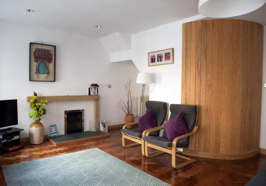 een woonkamer met 2 stoelen en een open haard bij The David Hume Residence in Edinburgh