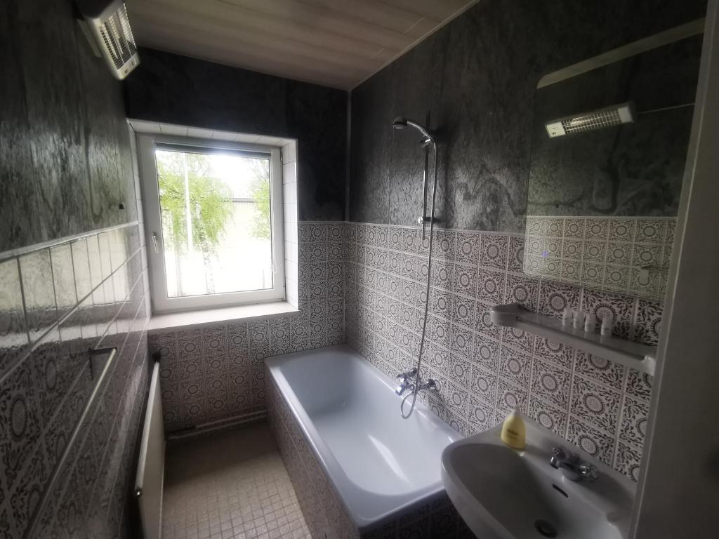 La salle de bains est pourvue d'une baignoire, d'un lavabo et d'une fenêtre. dans l'établissement Ferienwohnung Solebad, à Gmünd