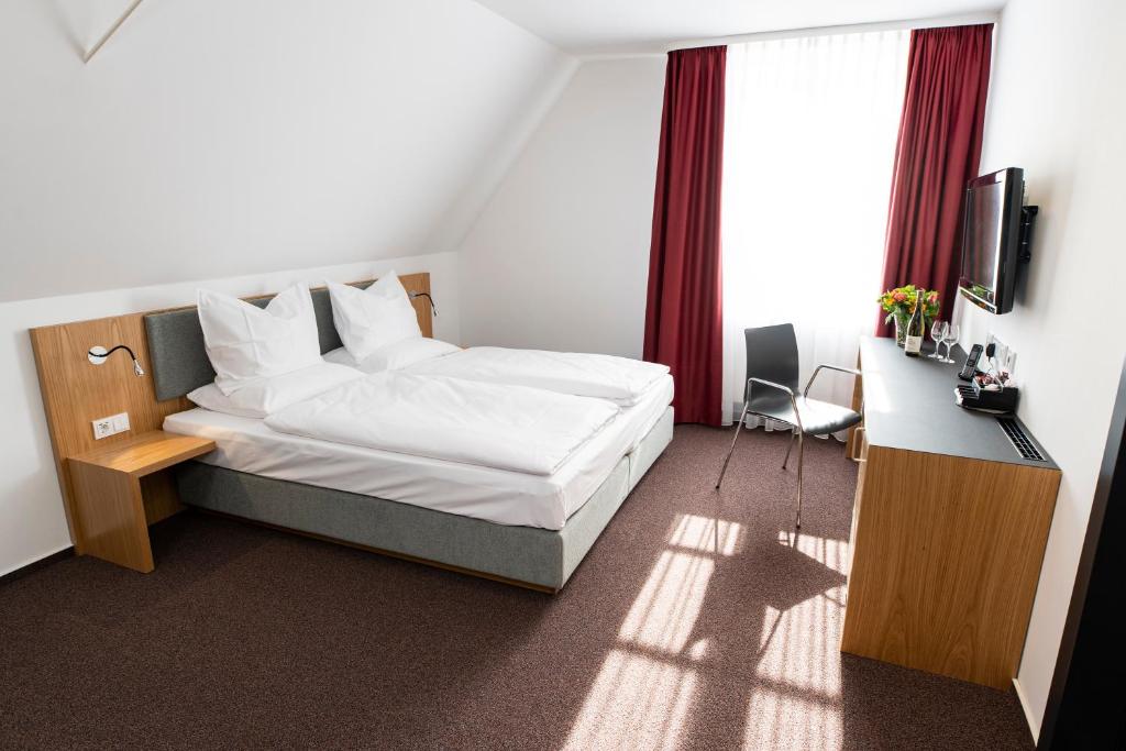 a bedroom with a bed and a desk and a television at Hotel Kloster Eberbach in Eltville