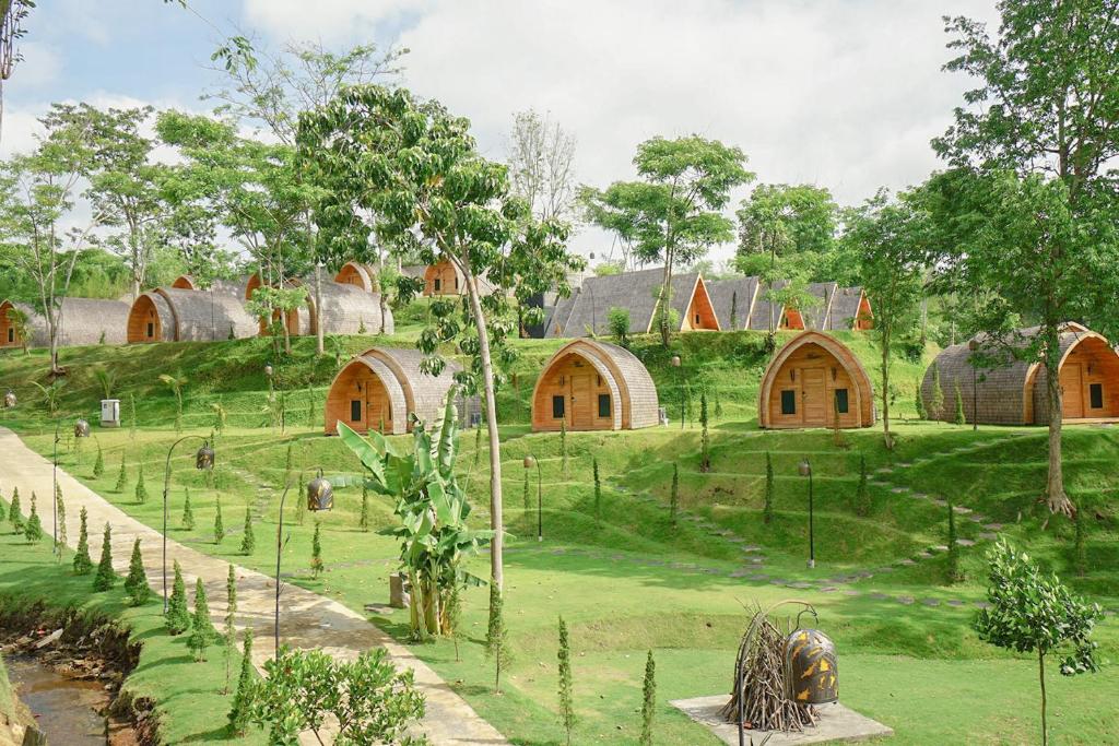 a group of buildings on a green field with trees at Shanaya Resort Malang in Malang