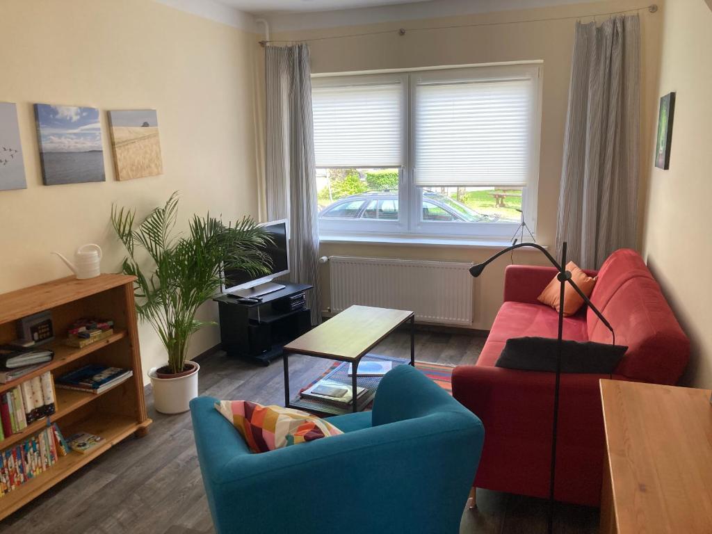 a living room with a red couch and two chairs at Ferienwohnung Nunatak am Plöner See in Dersau