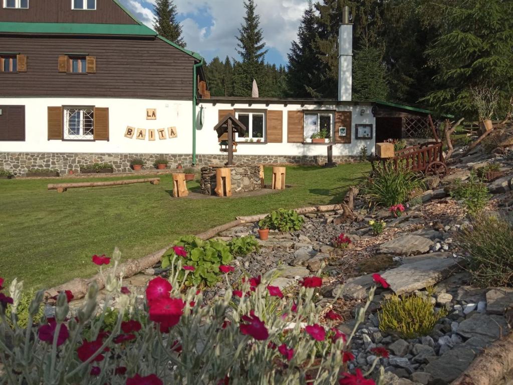 einen Garten vor einem Haus mit Blumen in der Unterkunft Penzion La Baita in Branná