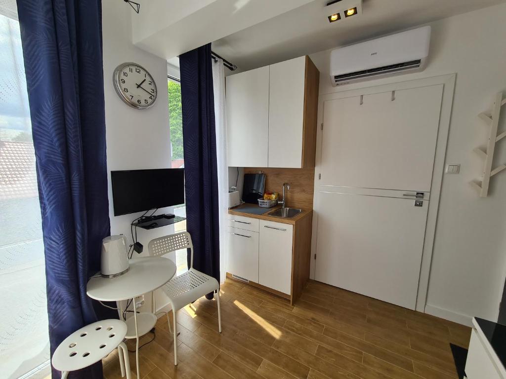 a small kitchen with a table and a clock on the wall at ApartHome K8 Centrum Sulęcin in Sulęcin