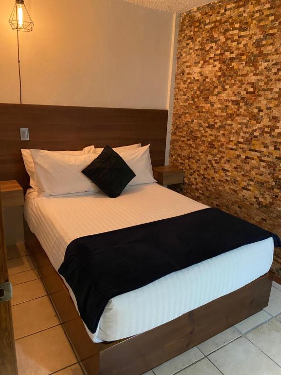 una camera con un grande letto con un muro di mattoni di Hotel Orquídea a Zacatlán
