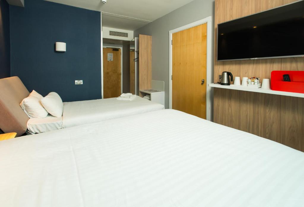 a bedroom with a large white bed and a flat screen tv at Holiday Inn Express Ramsgate – Minster by IHG in Minster
