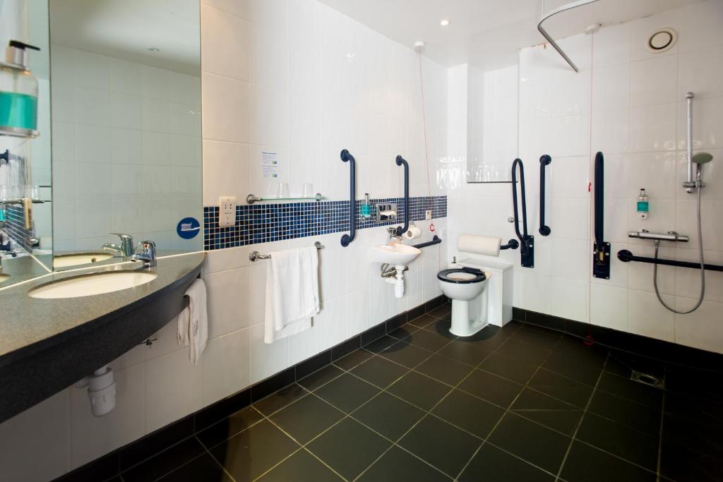 a bathroom with two sinks and a toilet and a shower at Holiday Inn Express Ramsgate – Minster by IHG in Minster
