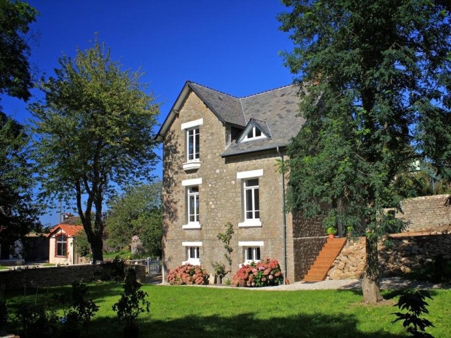 a large brick house with trees and a yard at Les Gites de la Laiterie de Tocqueville in Tocqueville
