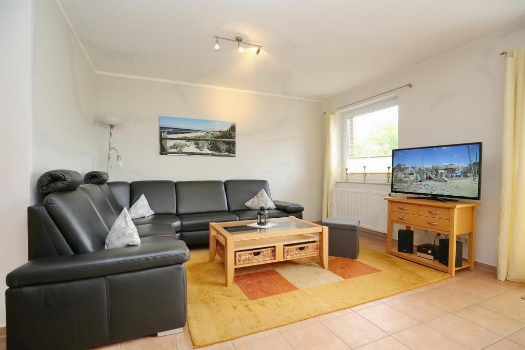a living room with a black leather couch and a television at Malaga Wohnung 3 in Boltenhagen