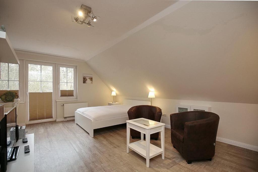 a bedroom with a bed and two chairs and a table at Strandvilla Krabbe Wohnung 14 in Boltenhagen