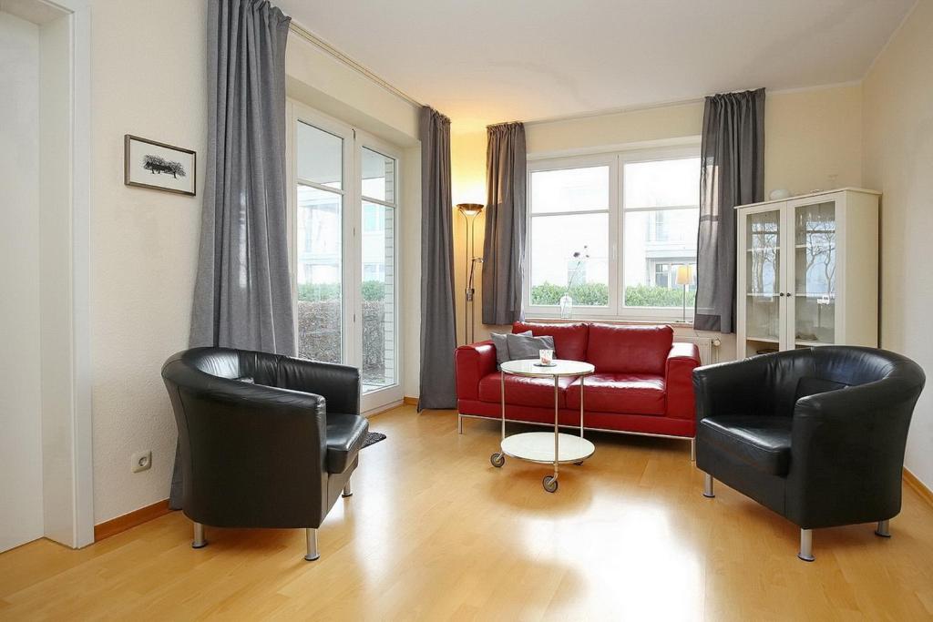 a living room with a red couch and chairs at Dünenblick Wohnung 35 in Boltenhagen