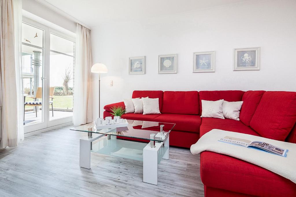 a living room with a red couch and a table at Dünenblick Wohnung 22 in Boltenhagen