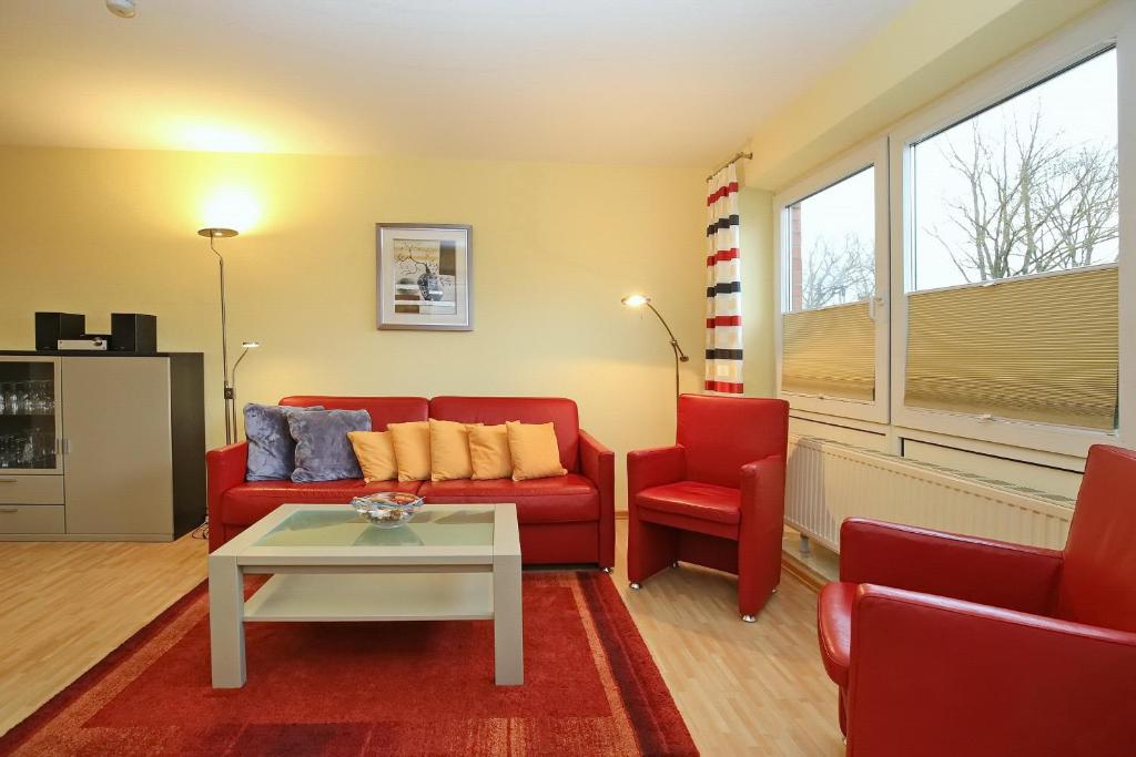 a living room with a red couch and two chairs at Goosbrink Wohnung 08 in Boltenhagen