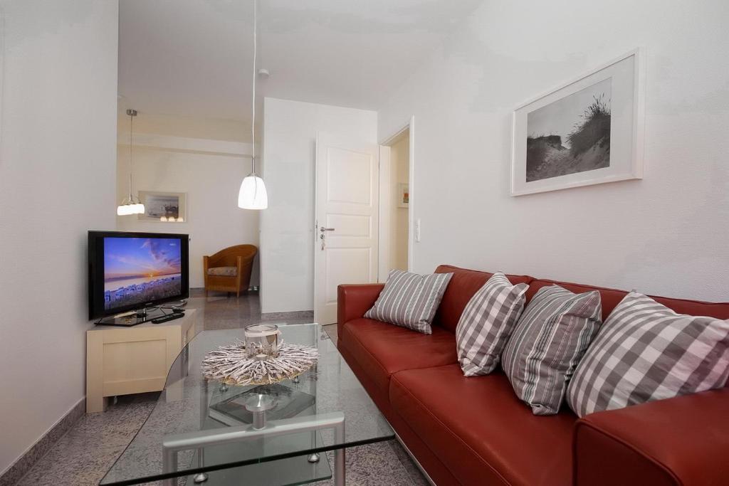 a living room with a red couch and a tv at Strandvilla Niklot Wohnung 03 in Boltenhagen