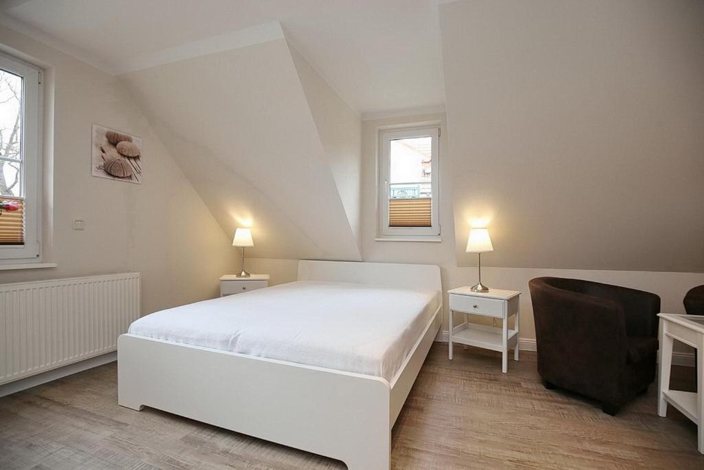 a white bedroom with a bed and two lamps at Strandvilla Krabbe Wohnung 10 in Boltenhagen