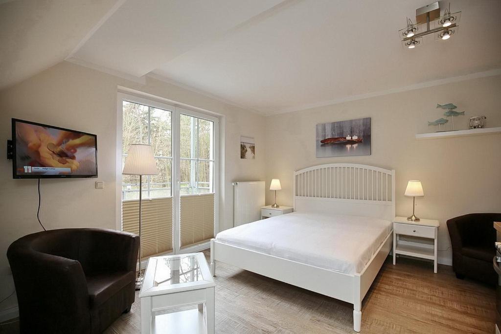 a bedroom with a white bed and a chair at Strandvilla Krabbe Wohnung 11 in Boltenhagen