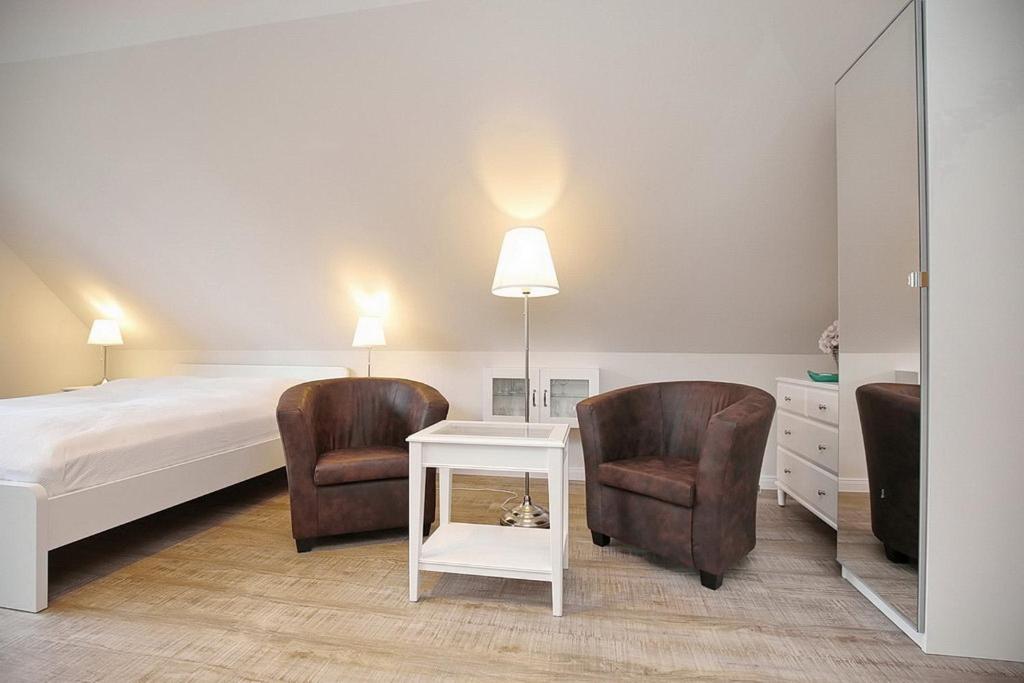 a bedroom with a bed and two chairs and a table at Strandvilla Krabbe Wohnung 13 in Boltenhagen