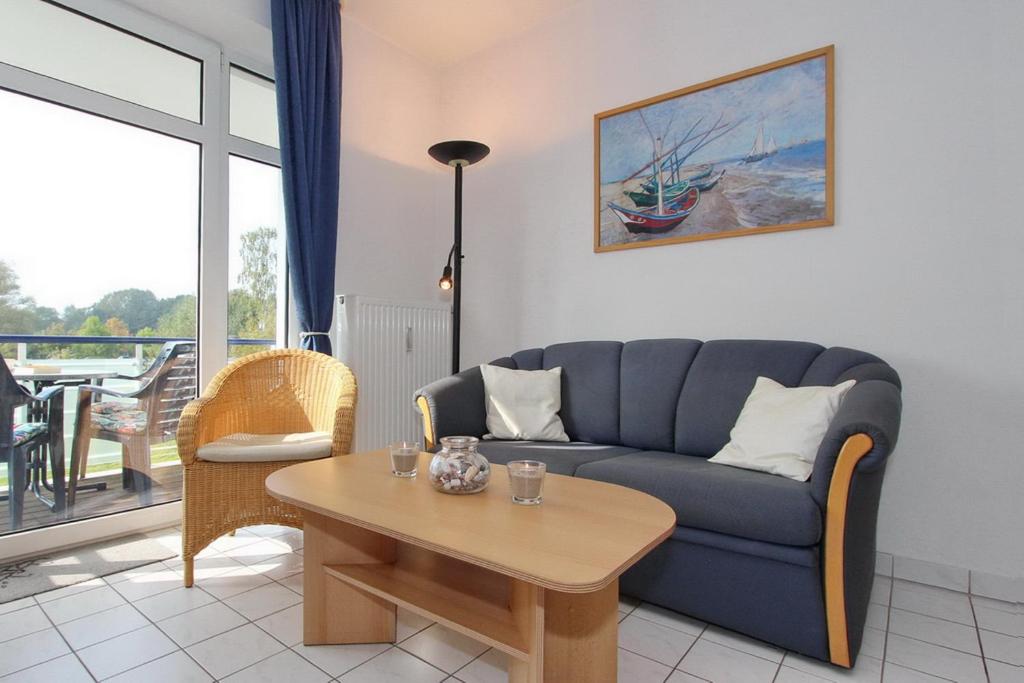 a living room with a blue couch and a table at Haffblick Wohnung 25 in Boltenhagen