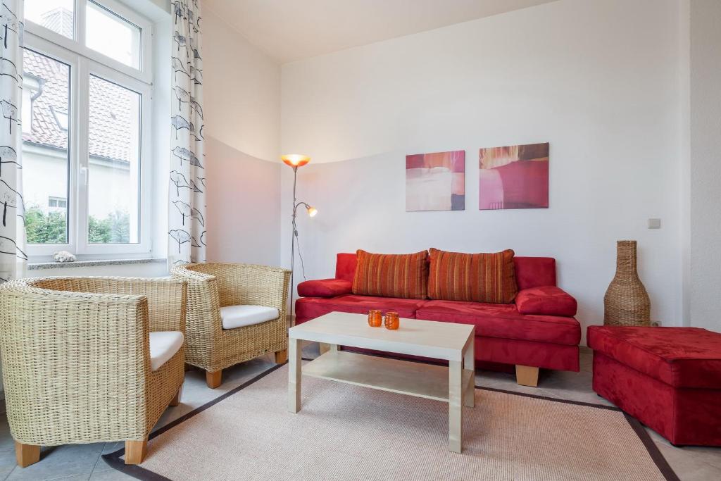 ein Wohnzimmer mit einem roten Sofa und Stühlen in der Unterkunft Villa Triton Wohnung 02 in Boltenhagen