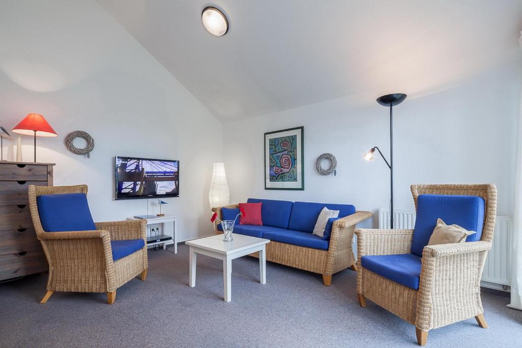 a living room with chairs and a blue couch at Godewind Wohnung 21 in Boltenhagen