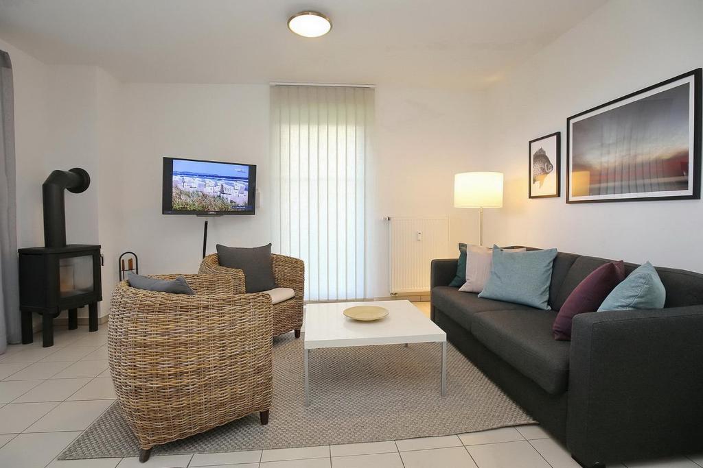 a living room with a couch and chairs and a tv at Strandvilla Niklot Wohnung 04 in Boltenhagen