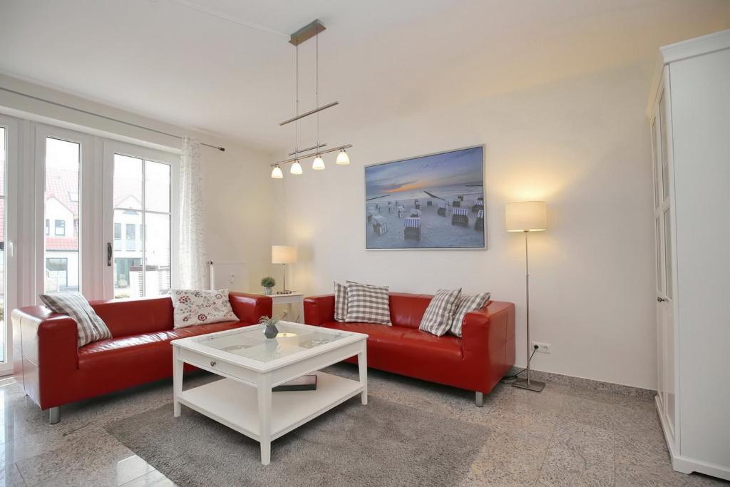 ボルテンハーゲンにあるStrandvilla Niklot Wohnung 01のリビングルーム(赤いソファ、テーブル付)