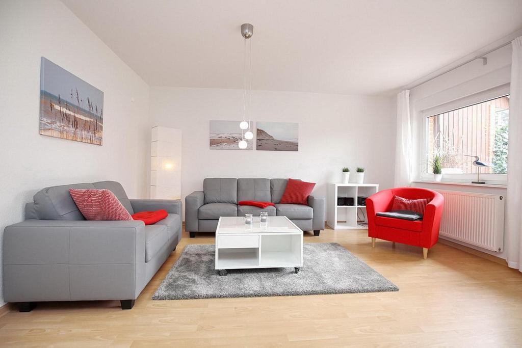 a living room with a couch and a red chair at Urlauberdorf Haus 21b in Boltenhagen