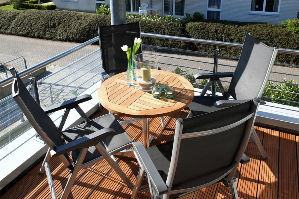 a table and chairs on a balcony with a table and flowers at Dünenblick Wohnung 09 in Boltenhagen