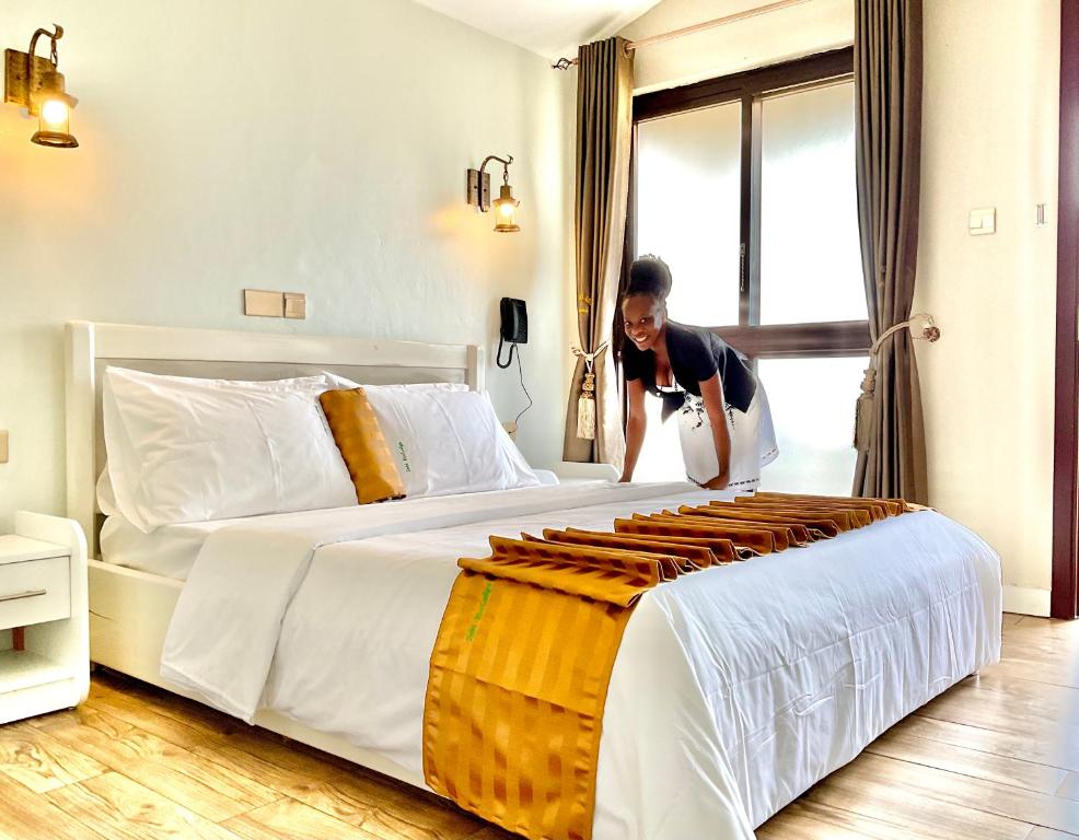 a woman is standing next to a large bed at Zebi Ecolodge in Hoima