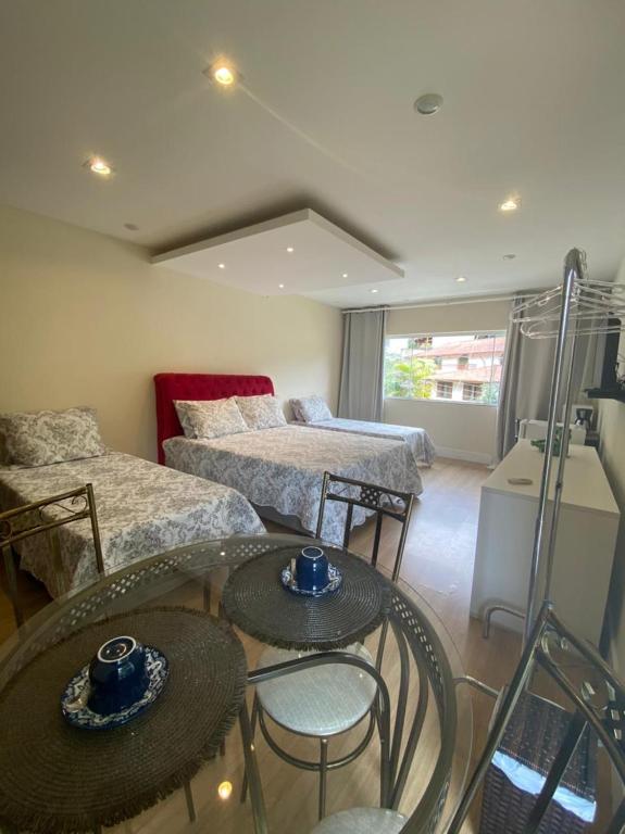a room with two beds and a table with chairs at Aconchego Serra Imperial - Suítes in Petrópolis