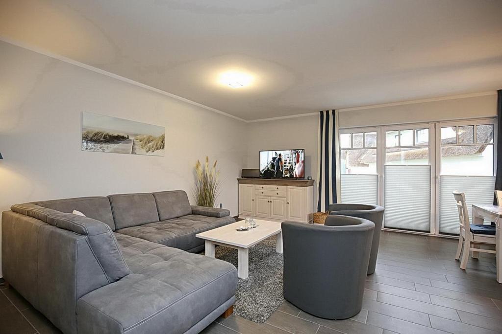 ein Wohnzimmer mit einem Sofa und einem Tisch in der Unterkunft Reethaus Am Mariannenweg 01a - Sylt in Boltenhagen