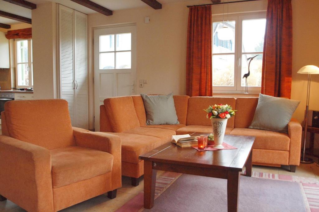 a living room with orange couches and a coffee table at Ferienhaus Hanni in Wittenbeck