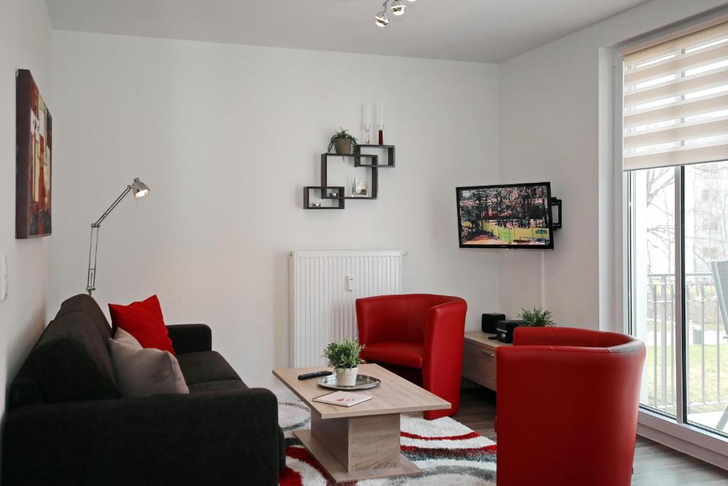 een woonkamer met 2 rode stoelen en een tafel bij Residenz von Flotow Wohnung 12 in Heiligendamm