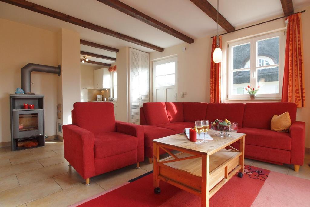 a living room with a red couch and two chairs at Ferienhaus Nanni in Wittenbeck
