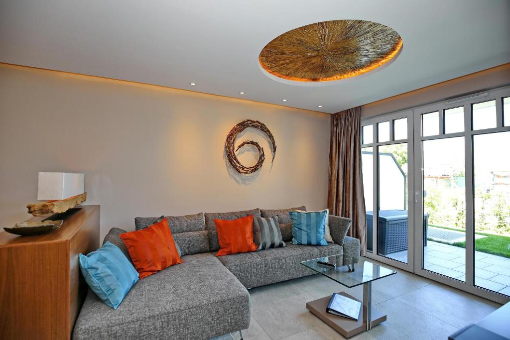 a living room with a gray couch with orange and blue pillows at Linden-Palais Wohnung 01 in Heiligendamm